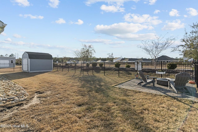 view of yard featuring an outbuilding, an outdoor fire pit, a storage unit, and fence