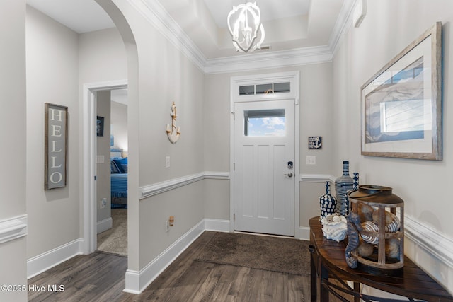 entrance foyer with a tray ceiling, arched walkways, baseboards, and dark wood-style floors