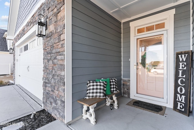 doorway to property featuring stone siding and a garage