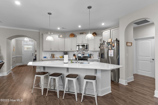 kitchen featuring visible vents, a sink, backsplash, stainless steel appliances, and arched walkways