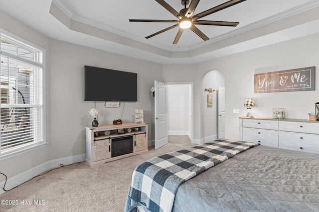 bedroom featuring a tray ceiling, light carpet, arched walkways, and ornamental molding