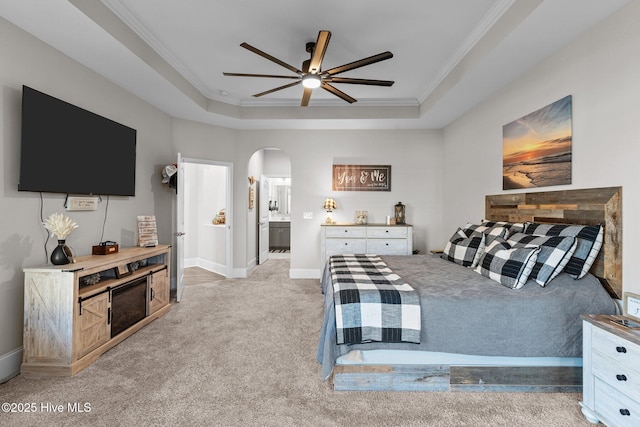 bedroom featuring a tray ceiling, crown molding, carpet, and arched walkways