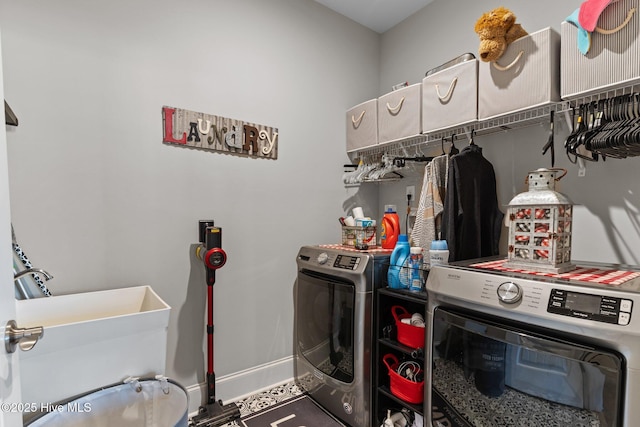 laundry room featuring a sink, baseboards, laundry area, and washing machine and clothes dryer