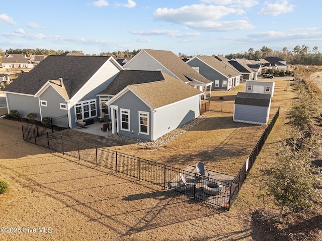 rear view of house featuring a residential view, a storage shed, a fenced backyard, an outbuilding, and a patio area