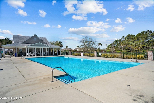 community pool with a patio area and fence