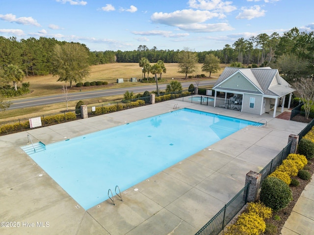 community pool with a patio area and fence