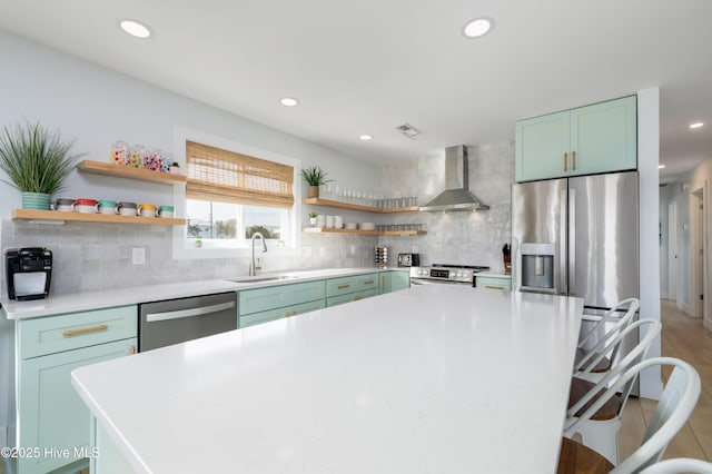 kitchen featuring open shelves, stainless steel appliances, a sink, a kitchen island, and wall chimney exhaust hood