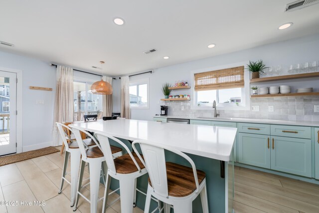 kitchen featuring open shelves, light countertops, visible vents, backsplash, and a sink