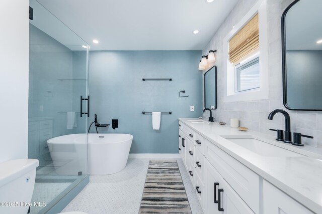 bathroom featuring toilet, a freestanding bath, baseboards, and a sink