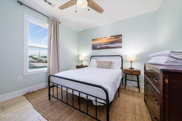 bedroom with ceiling fan, light wood finished floors, visible vents, and baseboards