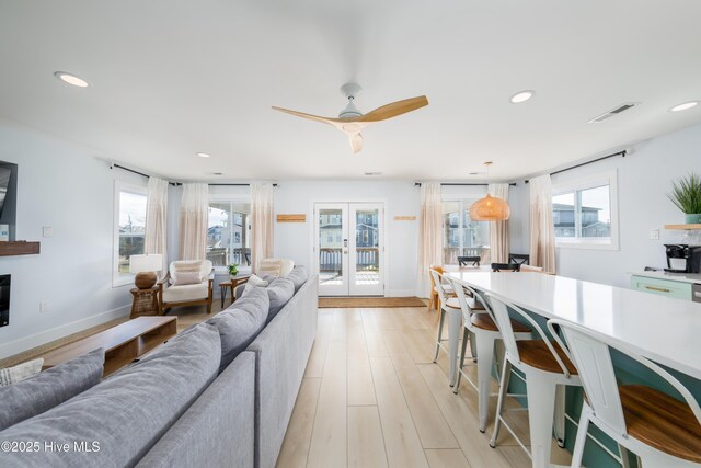 living room with light wood-style floors, a wealth of natural light, french doors, and visible vents