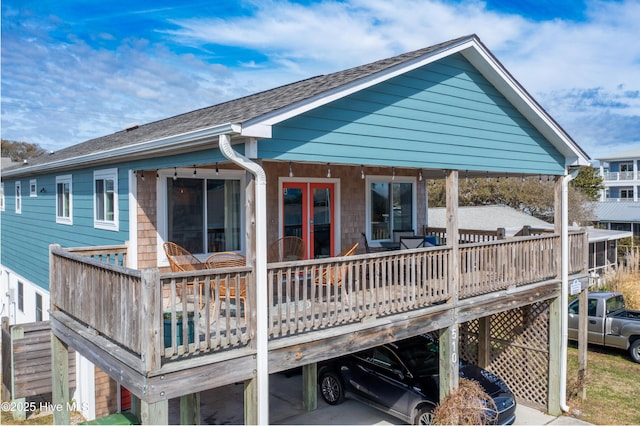 back of house with a deck, french doors, and a shingled roof