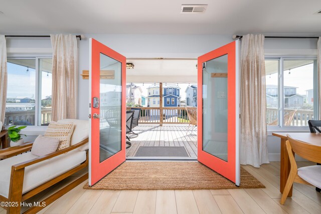 doorway to outside featuring plenty of natural light, visible vents, wood finished floors, and french doors