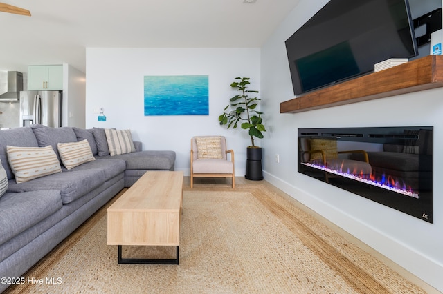 living area with baseboards and a glass covered fireplace