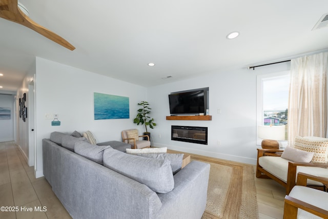 living room featuring recessed lighting, visible vents, baseboards, and a glass covered fireplace