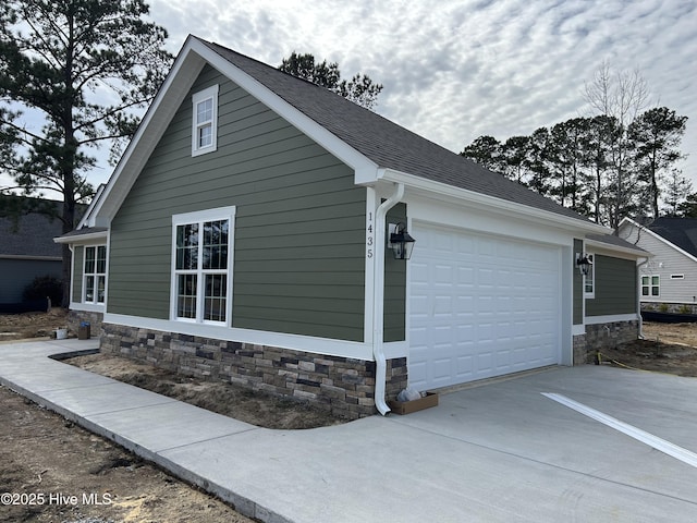 view of home's exterior featuring stone siding, driveway, and a garage