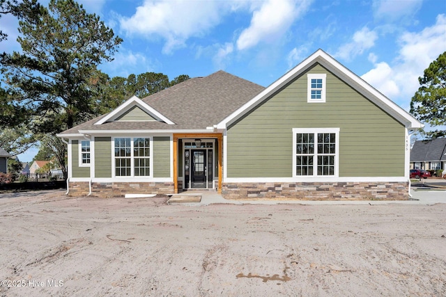 view of front of home with stone siding and a shingled roof