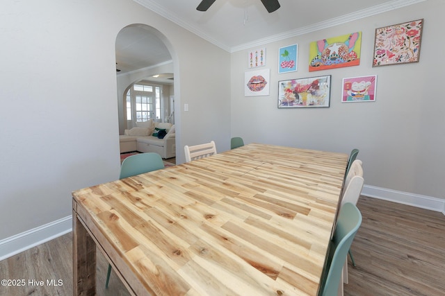 dining area featuring baseboards, arched walkways, wood finished floors, and ornamental molding
