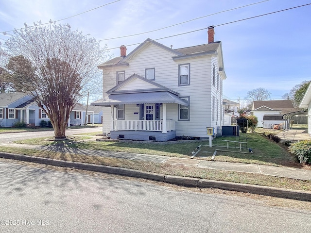 traditional style home with a porch, crawl space, a chimney, and a front lawn