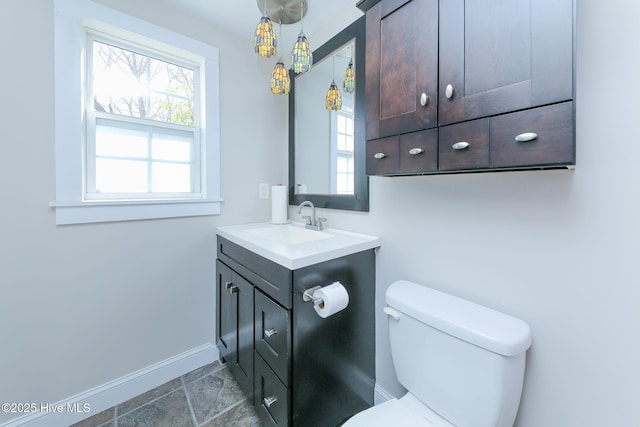 half bathroom featuring a wealth of natural light, baseboards, vanity, and toilet