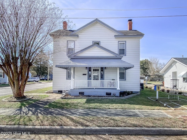 view of front facade with a porch, a front yard, and a chimney