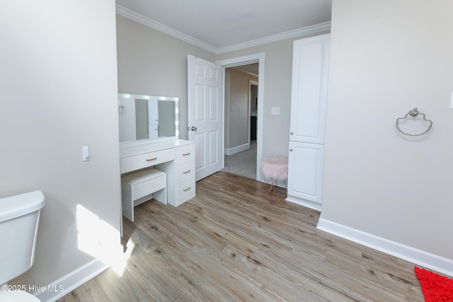 bathroom featuring ornamental molding, toilet, baseboards, and wood finished floors