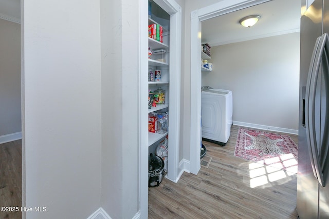 laundry room featuring laundry area, separate washer and dryer, wood finished floors, baseboards, and ornamental molding