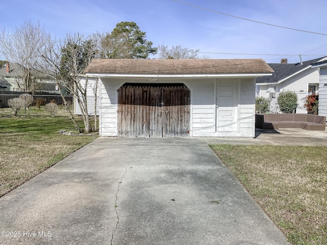 detached garage featuring fence and driveway