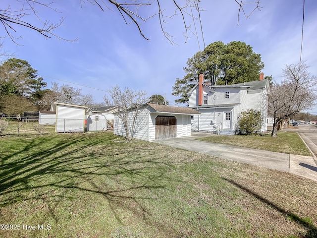 view of front of property featuring a chimney, an outbuilding, a storage unit, fence, and a front lawn