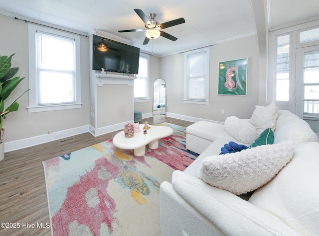 living area with ornamental molding, wood finished floors, and baseboards