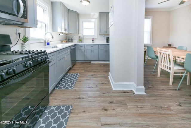 kitchen featuring stainless steel appliances, light wood-type flooring, gray cabinets, and crown molding