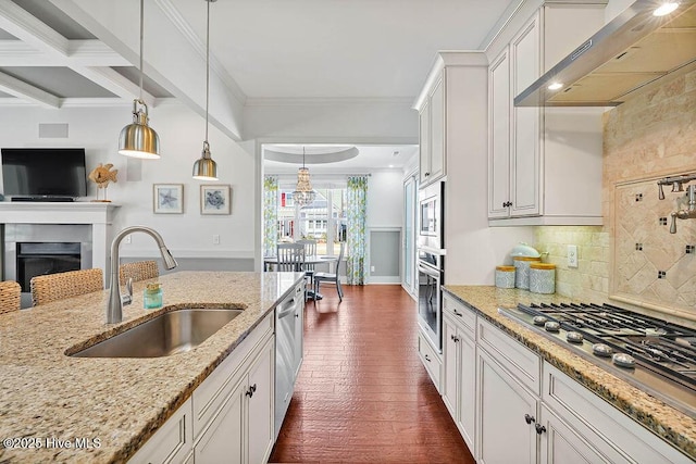 kitchen with tasteful backsplash, wall chimney exhaust hood, appliances with stainless steel finishes, crown molding, and a sink