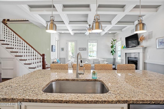 kitchen with hanging light fixtures, a fireplace, open floor plan, and a sink