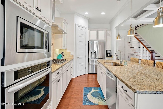 kitchen with ornamental molding, decorative light fixtures, a sink, stainless steel appliances, and backsplash