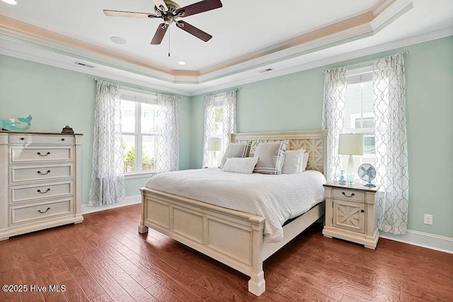 bedroom featuring dark wood-type flooring, a raised ceiling, visible vents, and crown molding