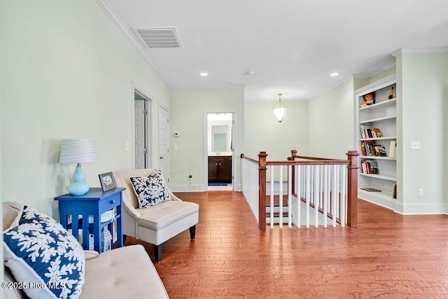 living area featuring visible vents, ornamental molding, wood finished floors, and an upstairs landing