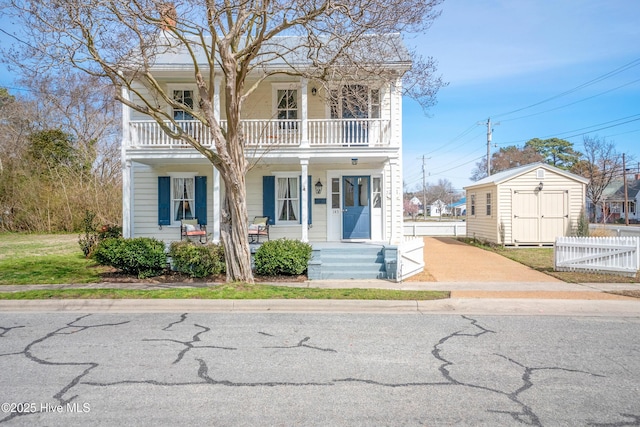 view of front of home with an outdoor structure, a balcony, fence, and covered porch