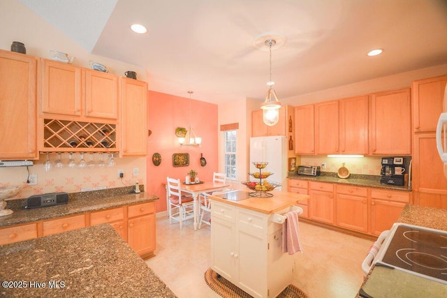 kitchen with freestanding refrigerator, light brown cabinets, and electric stove