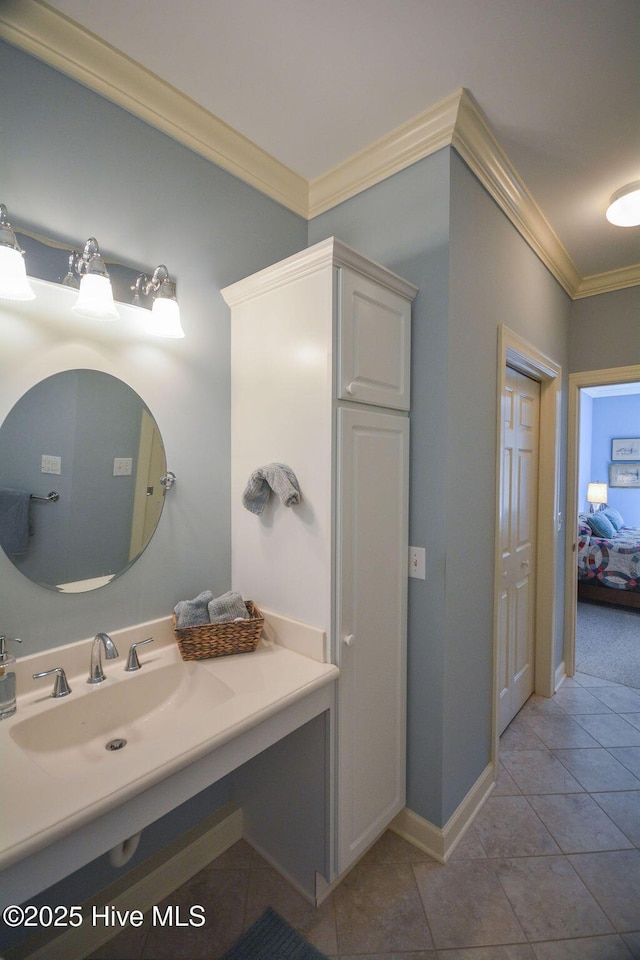 bathroom featuring tile patterned floors, ornamental molding, baseboards, and a sink