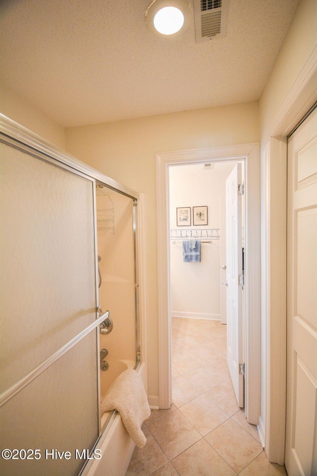 bathroom with visible vents, a textured ceiling, shower / bathing tub combination, tile patterned flooring, and baseboards