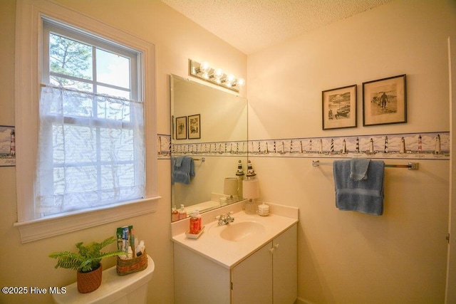 half bath featuring a wainscoted wall, toilet, a textured ceiling, and vanity