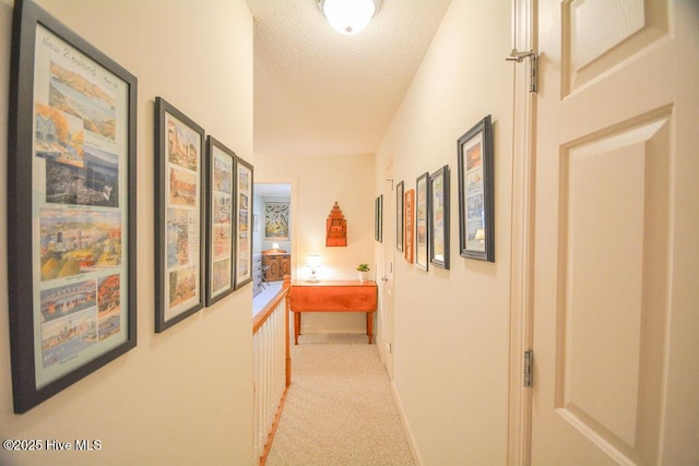 corridor with light colored carpet and a textured ceiling