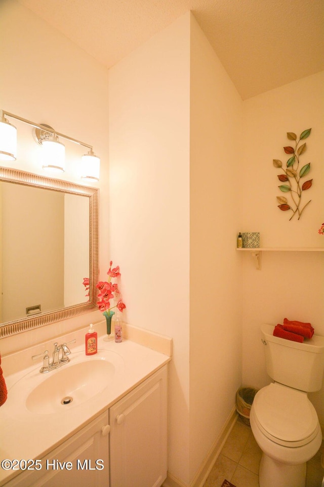 half bath featuring tile patterned floors, baseboards, toilet, and vanity