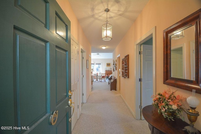 hall featuring baseboards and light carpet