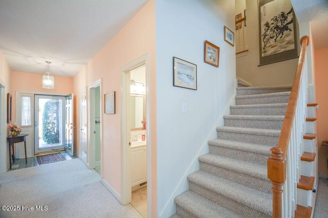 carpeted entryway featuring stairway and baseboards