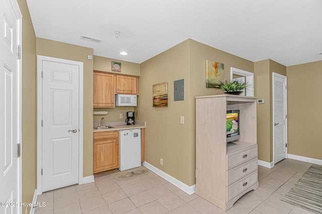 kitchen featuring white appliances, light tile patterned floors, visible vents, light countertops, and a sink