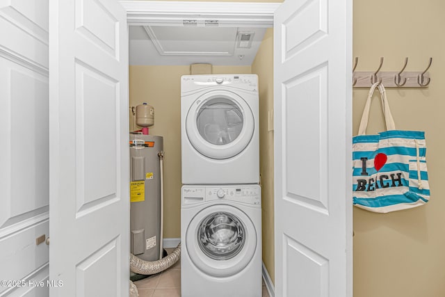 clothes washing area featuring laundry area, tile patterned flooring, water heater, and stacked washer / dryer