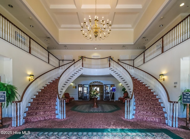 foyer featuring a towering ceiling, an inviting chandelier, coffered ceiling, beamed ceiling, and stairs