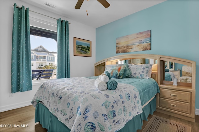 bedroom featuring ceiling fan, visible vents, baseboards, and wood finished floors