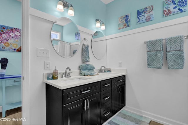 bathroom with double vanity, baseboards, and a sink